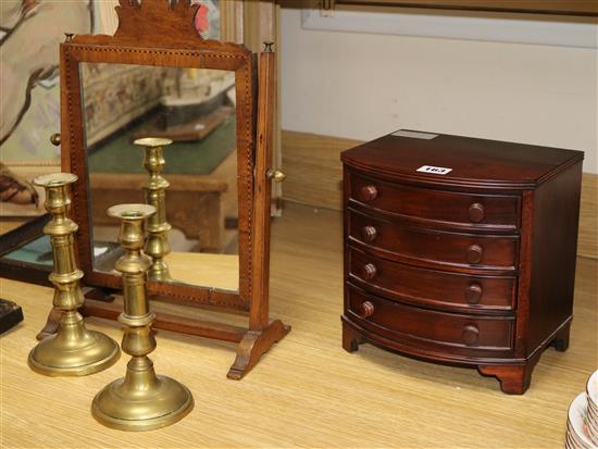 A mahogany toilet mirror, a pair of Victorian brass candlesticks and a miniature bowfronted chest of drawers (4)